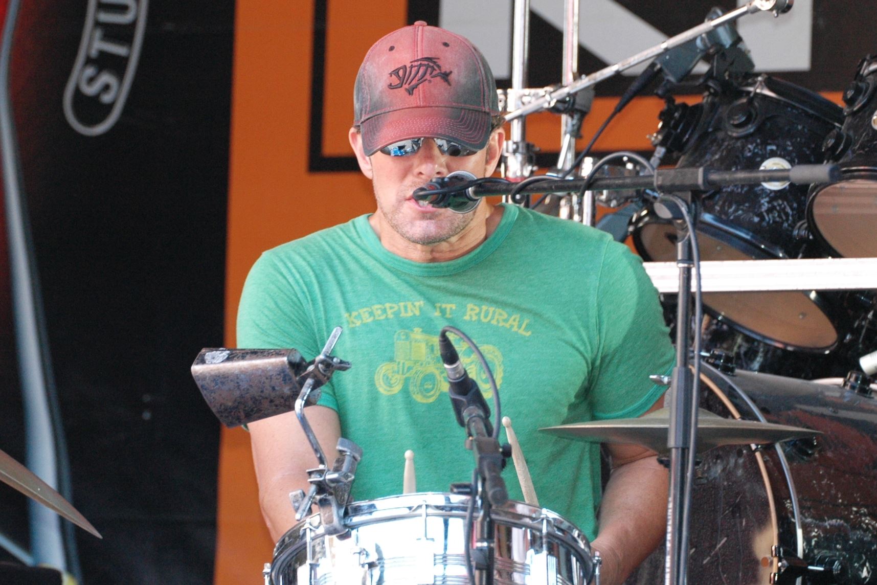Randy singing and playing drums on stage
